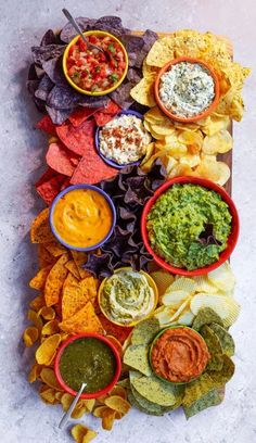 a platter with chips, salsa and guacamole dips on it