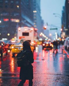 a woman is walking down the street in the rain with her back to the camera