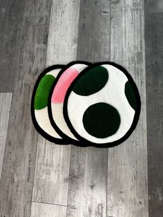 three round rugs with green and pink designs on them sitting on a wood floor