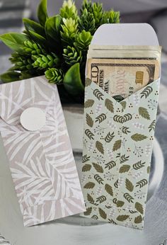 two small envelopes sitting on top of a table next to a potted plant