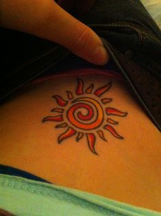 a person with a sun tattoo on their back and the other hand pointing at it