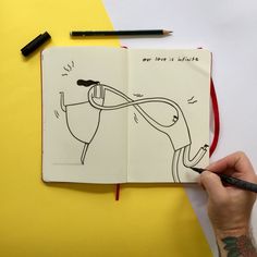 a hand holding a pencil over an open notebook with a drawing of a horse on it