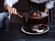 two people are preparing chocolate cake on a table