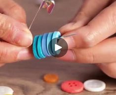 two hands are working with buttons on a wooden table and one person is holding an object in their hand