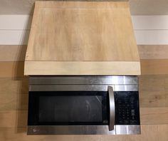 a stainless steel microwave oven mounted on a wooden counter