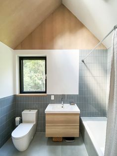 a bathroom with a toilet, sink and bathtub next to a window in the ceiling