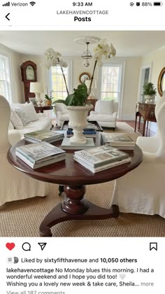 a living room filled with white furniture and lots of books on top of a table