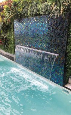 an outdoor pool with a waterfall and tiled walls