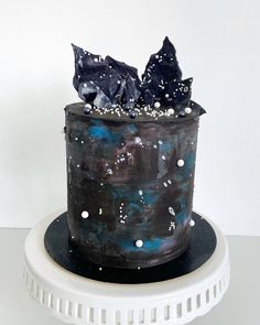 a black cake with blue frosting and white sprinkles