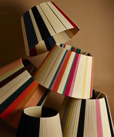 multicolored lampshades stacked on top of each other in front of a brown background