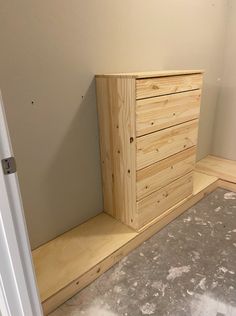 a wooden dresser sitting on top of a floor next to a white door in a room