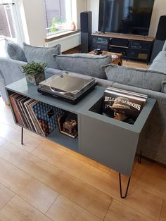 a living room with couches and a television on top of a wooden table in front of a window