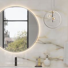 a bathroom with a round mirror on the wall next to a white sink and counter