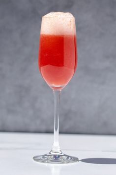 a glass filled with liquid sitting on top of a white table next to a gray wall