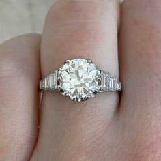 a woman's engagement ring with baguetts and side stones on her finger