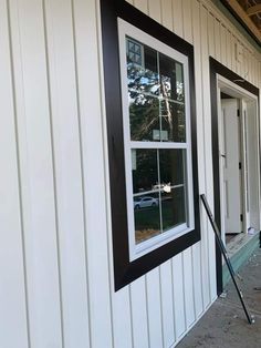 a white house with black trim on the windows and door is being worked on by a worker