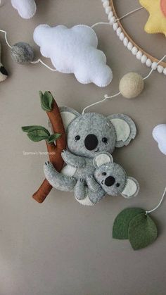 there is a stuffed koala bear hanging from a tree with two baby koalas on it