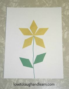 a flower made out of paper sitting on top of a sheet of white paper with yellow and green leaves