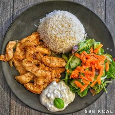 a plate with rice, salad and chicken on it next to a side of dressing