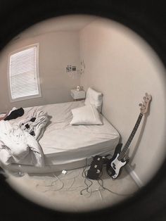 a bed room with a guitar on the floor