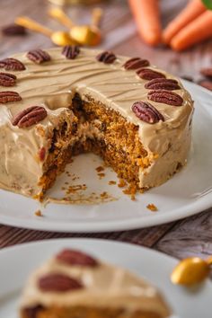 a carrot cake with frosting and pecans on the top is cut in half