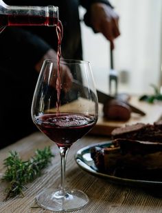 someone pouring red wine into a glass on a table