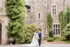 a bride and groom standing in front of an old stone building with ivy on it