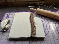 a piece of wood sitting on top of a cutting mat next to a rolling pin