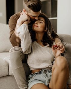 a man sitting on top of a couch next to a woman who is kissing her forehead