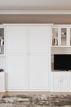 a living room with white cabinets and a large tv on top of a entertainment center