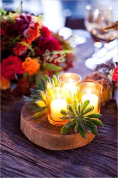 candles are lit on a wooden table with flowers