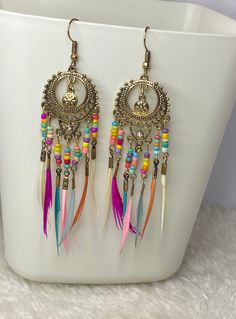 Festival Chic and Colourful Boho Feather Drop Earrings Product - P00009 Introducing our gorgeous Festival Chic and Colourful Boho Feather Drop Earrings, the accessory to add a pop of colour and style to your look!  Crafted with lightweight materials, these earrings are comfortable to wear all day long, making them suitable for any occasion. Each pair of earrings features an array of colourful feathers that dangle gracefully from a beautifully designed base. The intricate details of the design give these earrings an ethnic flair, making them a stunning accessory to pair with both casual and dressy outfits. Colourful Feathers, Festival Chic, Beautiful Stud Earrings, Bohemian Jewellery, Boho Feathers, Earrings Handmade Dangle, Colorful Feathers, Stylish Earring, Beaded Dangle Earrings