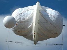 two large white balloons floating in the air with wires attached to it's sides