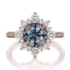 an engagement ring with a blue diamond surrounded by white and rose gold diamonds on the band