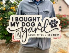 a man holding a sign that says, i bought my dog a yard against title and escrow