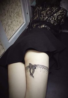 a woman's thigh with a bow tattoo on it