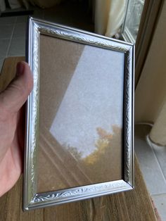 a person is holding up a silver frame