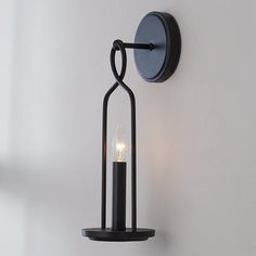 a candle is lit on the wall next to a light fixture with a curved handle