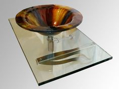 a glass bowl sink sitting on top of a clear counter next to a pair of scissors