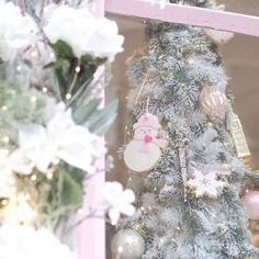 a decorated christmas tree in front of a window with pink and white ornaments on it