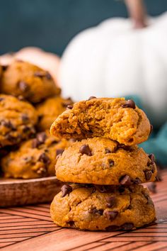 chocolate chip cookies stacked on top of each other in front of a pumpkin and white pumpkin