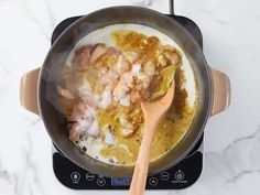 a pan filled with food sitting on top of a stove next to a wooden spoon