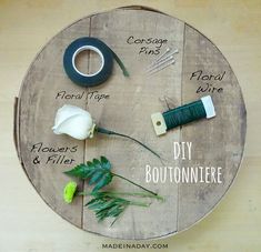 a round wooden table with flowers and scissors on it, labeled by the words diy boutonniere