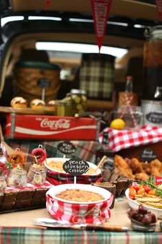 a table filled with lots of food on top of a wooden table covered in red and white checkered cloth