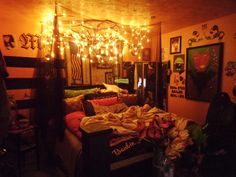 a bedroom with lights strung from the ceiling and bed covered in blankets, pillows and blankets