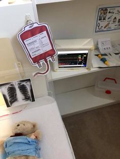 a teddy bear laying on a bed in a room with medical equipment and other items