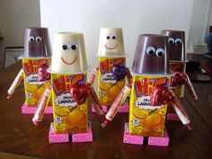 three chocolate candies in the shape of people holding candy bars with eyes and noses