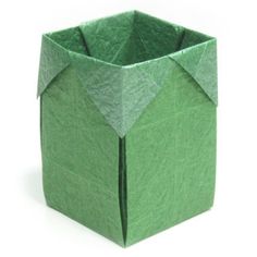 an origami box that is folded in green paper with the lid open to show the inside