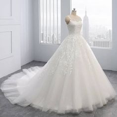 a wedding dress on display in front of a window with the city skyline behind it