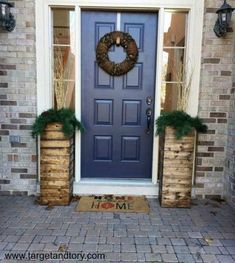 a blue front door with two planters and a wreath on the side entrance to a home